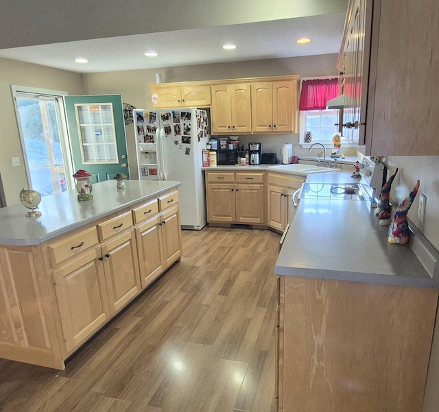 kitchen featuring sink, a center island, light brown cabinets, light wood-type flooring, and white fridge with ice dispenser