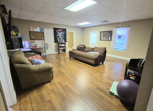 living room featuring a drop ceiling and light wood-type flooring