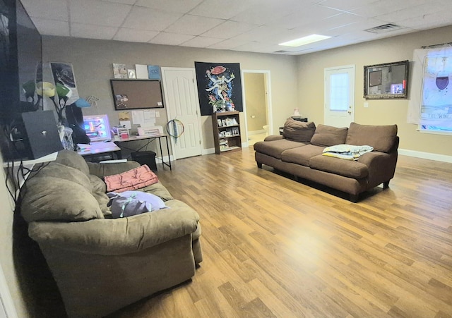 living room with light hardwood / wood-style floors and a paneled ceiling