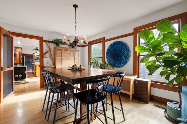 dining area featuring light hardwood / wood-style flooring and ceiling fan with notable chandelier