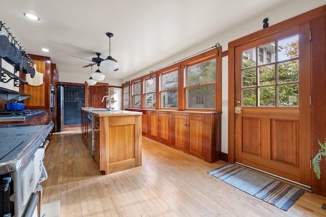 kitchen featuring white range, sink, ceiling fan, an island with sink, and light hardwood / wood-style floors