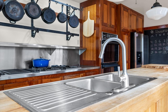 kitchen with butcher block countertops, backsplash, pendant lighting, and stainless steel refrigerator with ice dispenser