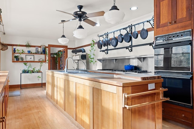 kitchen with ceiling fan, wooden counters, double oven, decorative light fixtures, and stainless steel gas stovetop