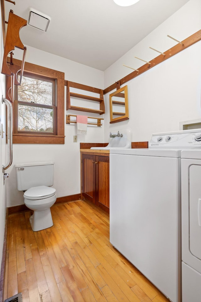 interior space featuring washing machine and clothes dryer, sink, and light wood-type flooring