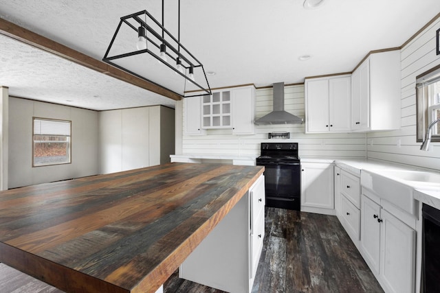 kitchen featuring black electric range oven, wall chimney exhaust hood, pendant lighting, white cabinetry, and butcher block counters