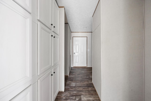 corridor with a textured ceiling and dark hardwood / wood-style floors