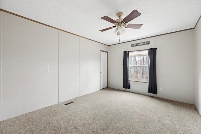 carpeted empty room featuring ceiling fan, a textured ceiling, and ornamental molding