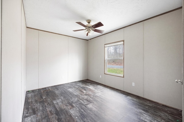 empty room with a textured ceiling, crown molding, ceiling fan, and dark wood-type flooring