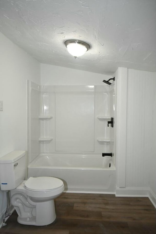 bathroom featuring toilet, hardwood / wood-style flooring, vaulted ceiling, and shower / bathtub combination