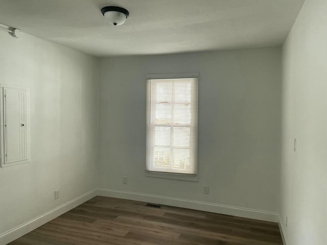 spare room featuring electric panel and dark wood-type flooring