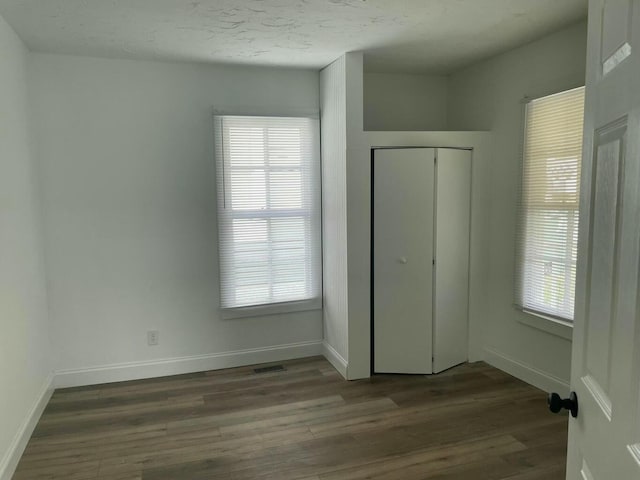 unfurnished bedroom featuring a closet, wood-type flooring, and multiple windows