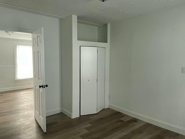 unfurnished bedroom featuring wood walls, a closet, and hardwood / wood-style flooring