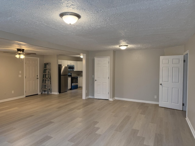 unfurnished living room featuring ceiling fan, light wood-type flooring, and a textured ceiling