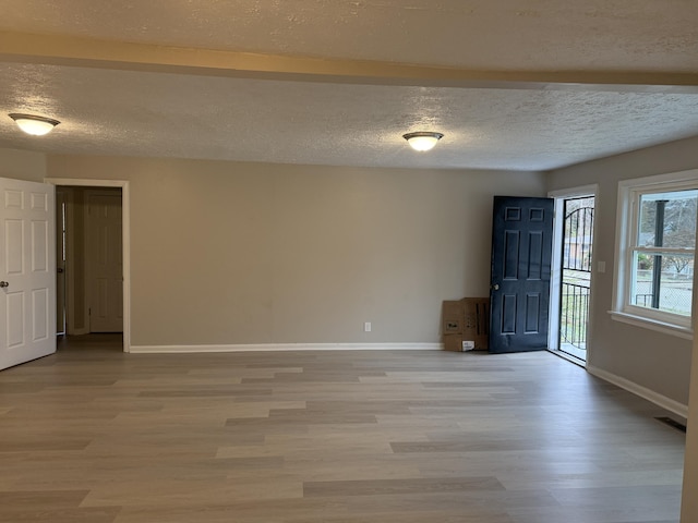 spare room featuring a textured ceiling and light hardwood / wood-style floors