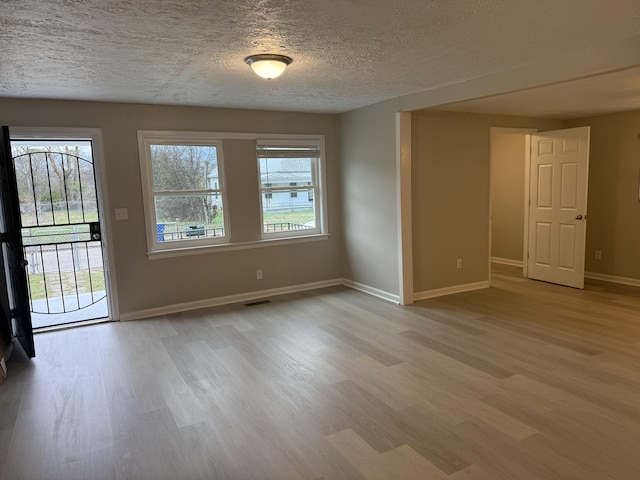 unfurnished room with light hardwood / wood-style floors and a textured ceiling