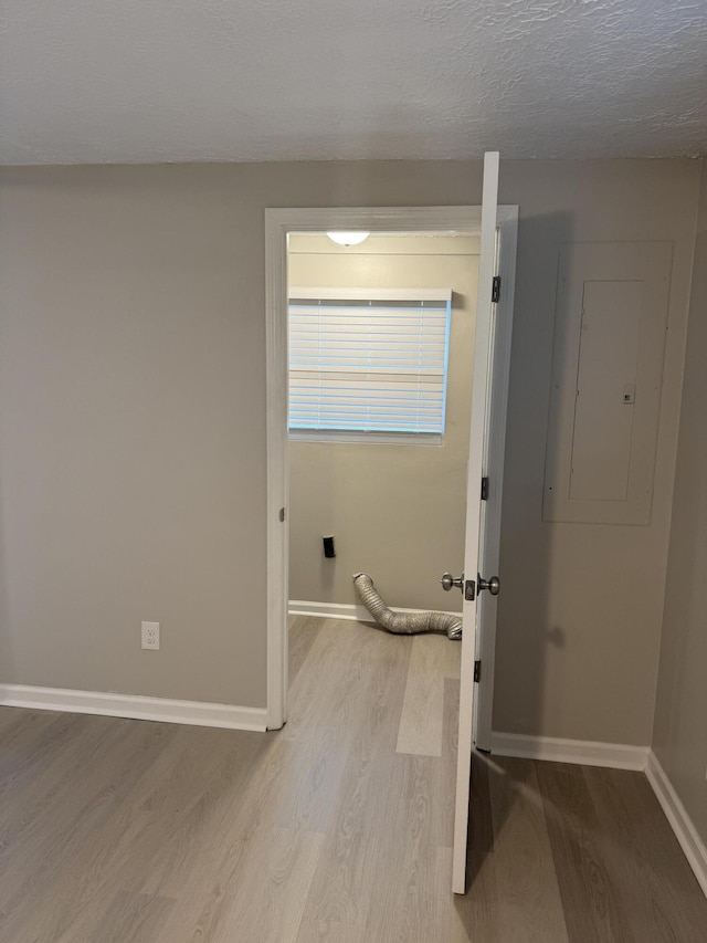 interior space featuring electric panel, a textured ceiling, and light wood-type flooring