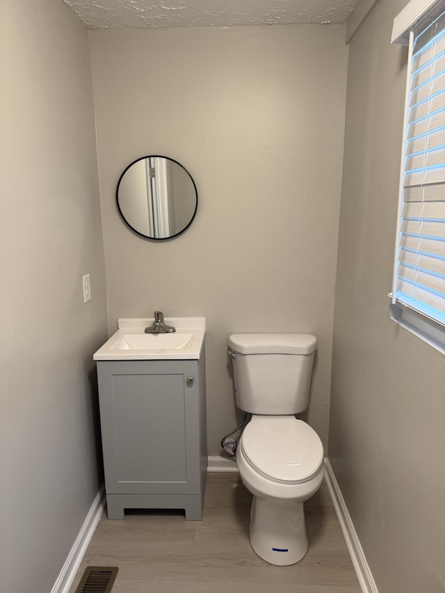 bathroom with a textured ceiling, vanity, hardwood / wood-style flooring, and toilet