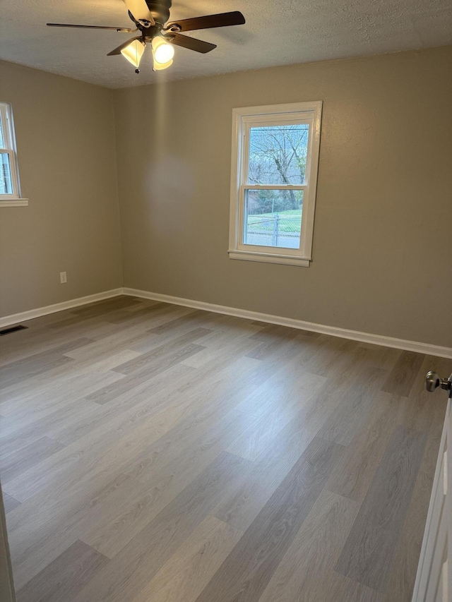 unfurnished room featuring a textured ceiling, light hardwood / wood-style floors, and ceiling fan