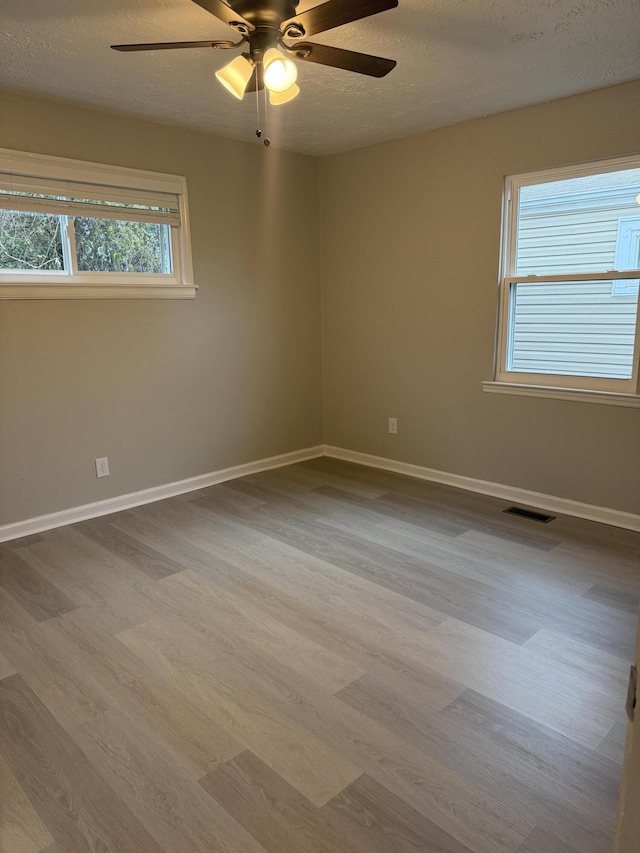 unfurnished room with a textured ceiling, light hardwood / wood-style flooring, and ceiling fan