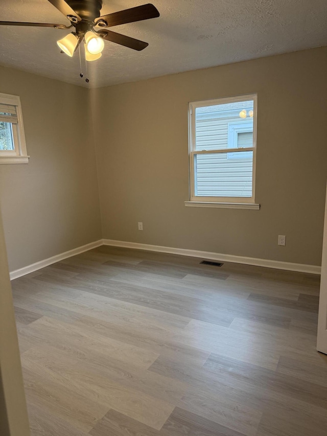 unfurnished room with ceiling fan, light wood-type flooring, and a textured ceiling