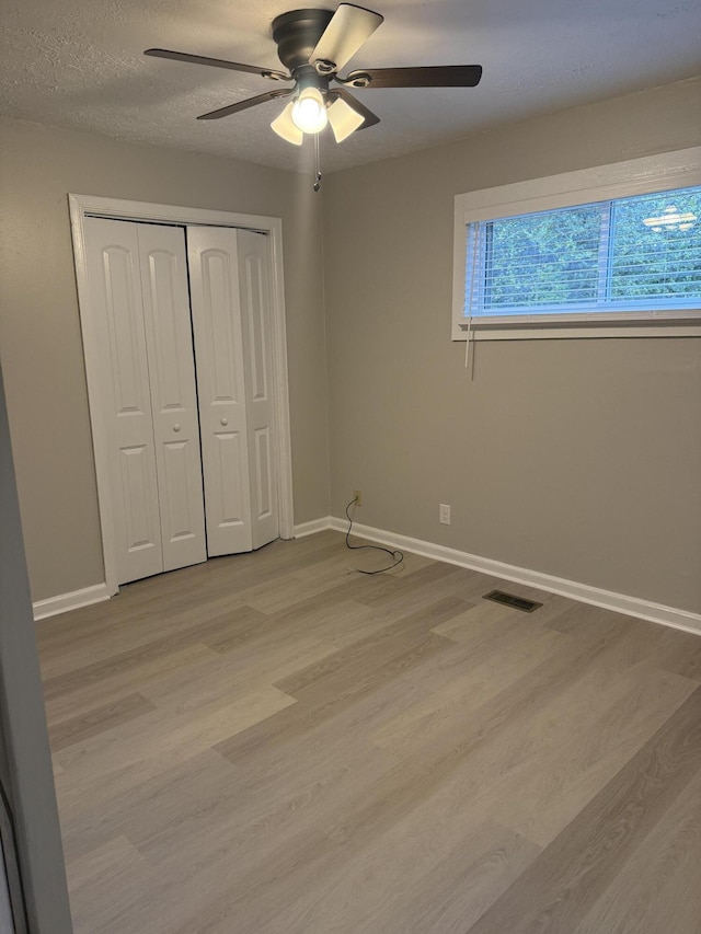 unfurnished bedroom featuring a closet, light hardwood / wood-style flooring, and ceiling fan