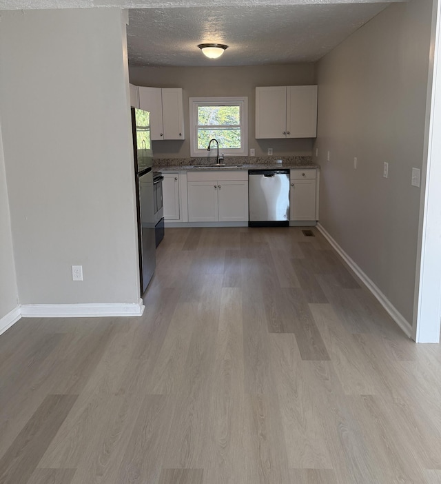 kitchen featuring sink, light wood-type flooring, a textured ceiling, white cabinetry, and stainless steel appliances