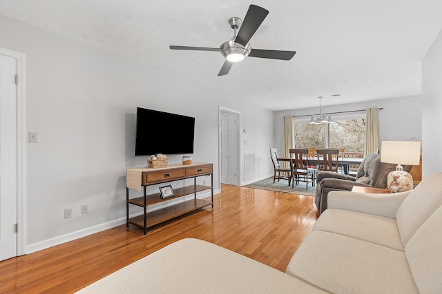 living room featuring a textured ceiling, ceiling fan with notable chandelier, and hardwood / wood-style flooring