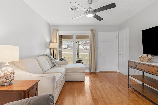 living room with ceiling fan, a textured ceiling, and light hardwood / wood-style flooring