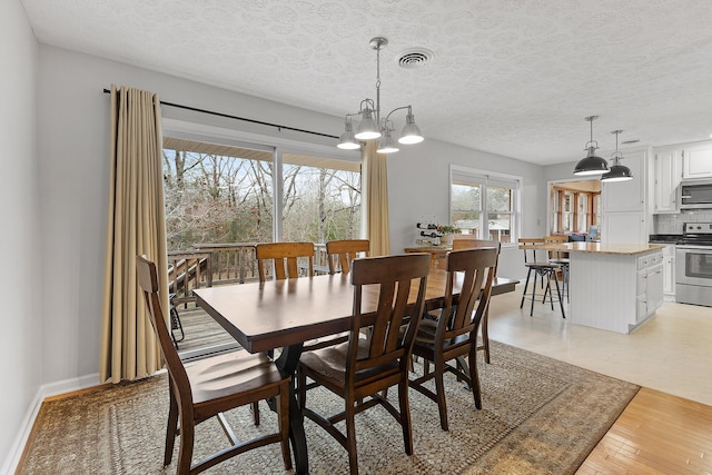 dining space featuring a chandelier, a textured ceiling, and light wood-type flooring