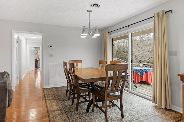 dining room featuring hardwood / wood-style floors, a textured ceiling, and a notable chandelier