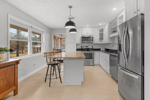 kitchen with appliances with stainless steel finishes, dark stone counters, sink, a center island, and white cabinetry