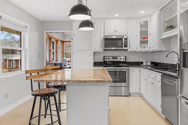 kitchen featuring white cabinets, hanging light fixtures, sink, appliances with stainless steel finishes, and a kitchen island