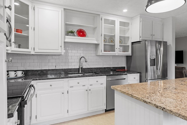 kitchen with white cabinetry, sink, dark stone counters, and appliances with stainless steel finishes