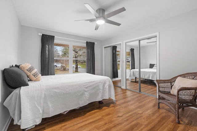 bedroom featuring ceiling fan, wood-type flooring, and two closets