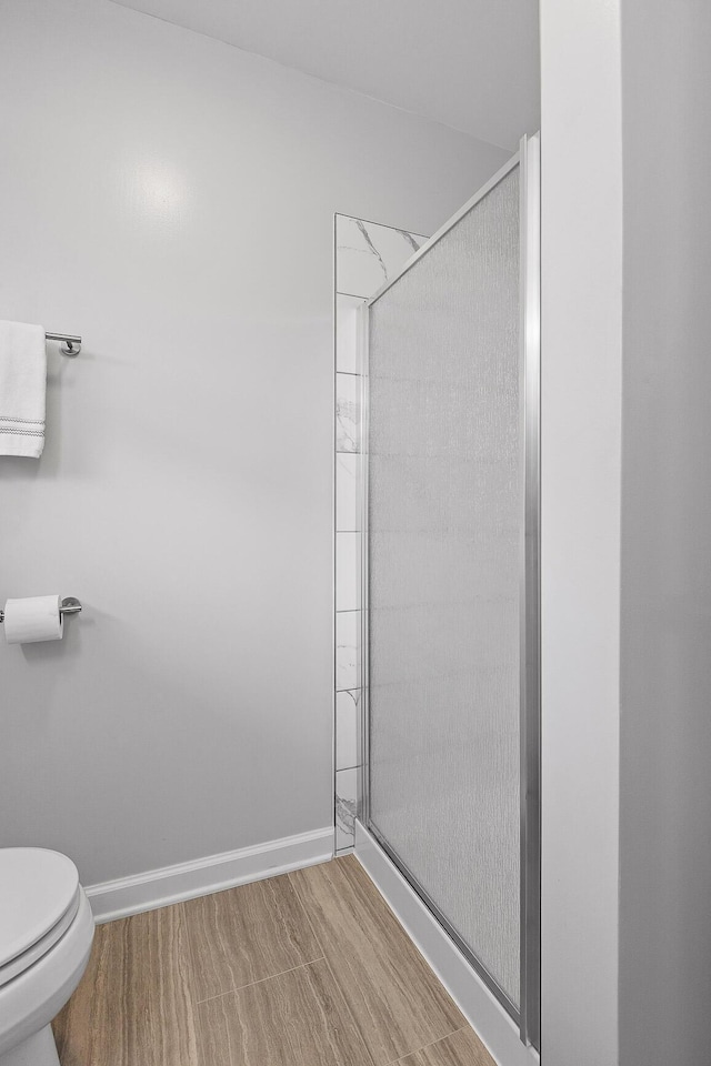 bathroom with wood-type flooring, an enclosed shower, and toilet