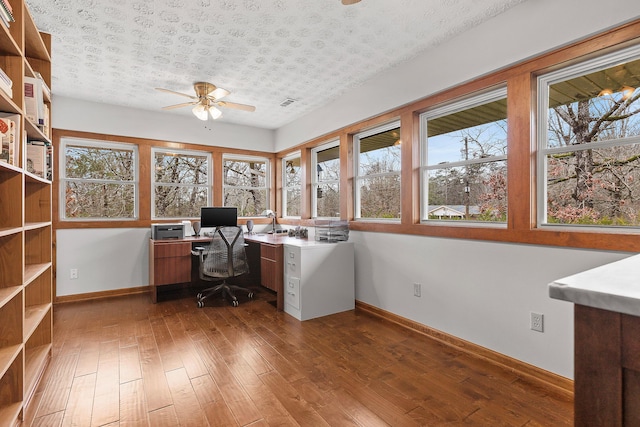 unfurnished office with ceiling fan, a healthy amount of sunlight, a textured ceiling, and hardwood / wood-style flooring