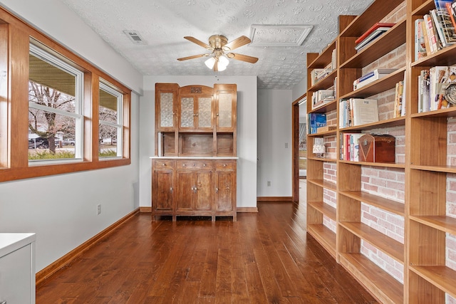 unfurnished office with ceiling fan, dark wood-type flooring, and a textured ceiling