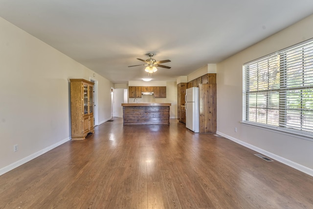 unfurnished living room featuring ceiling fan and dark hardwood / wood-style flooring