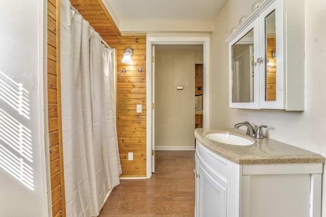 bathroom featuring hardwood / wood-style flooring, vanity, and wood walls