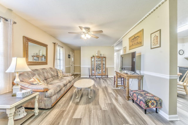 living room featuring a textured ceiling, hardwood / wood-style flooring, ceiling fan, and crown molding