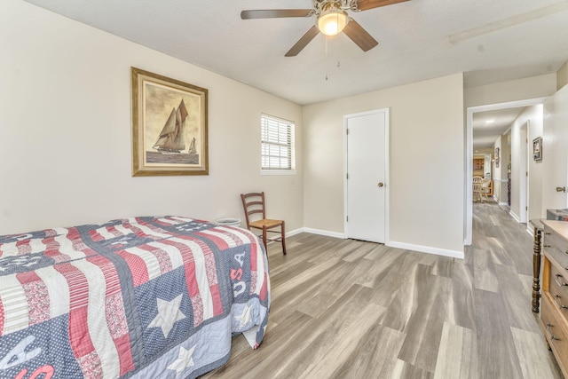 bedroom featuring ceiling fan, light wood-type flooring, and a textured ceiling