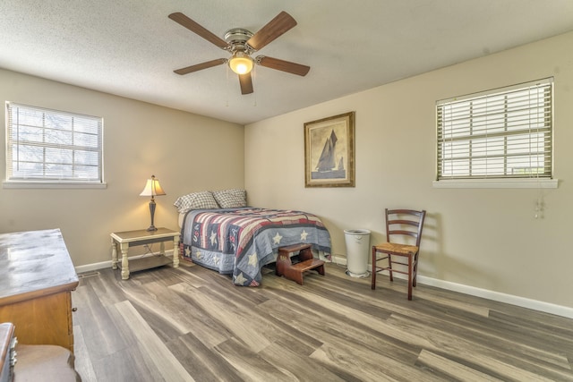 bedroom with a textured ceiling, hardwood / wood-style flooring, and ceiling fan