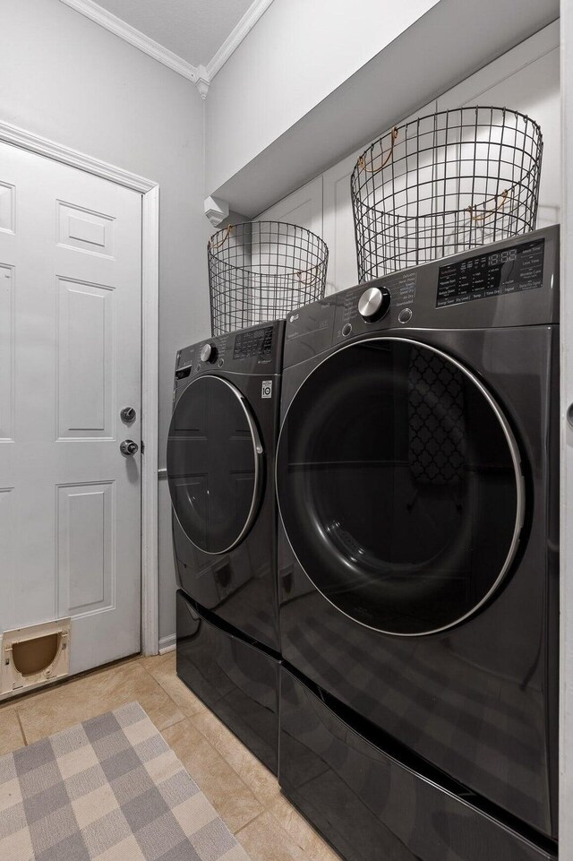 washroom with light tile patterned floors, ornamental molding, and washer and dryer