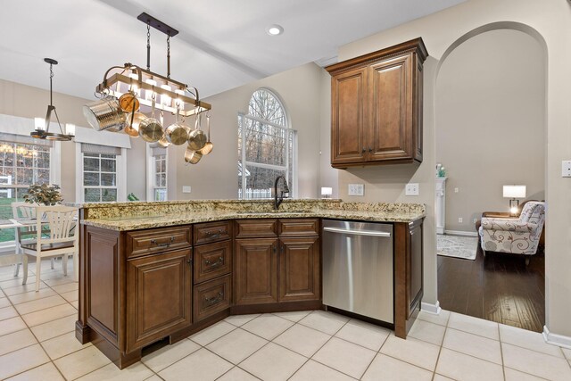 kitchen with sink, decorative light fixtures, stainless steel dishwasher, kitchen peninsula, and light stone countertops