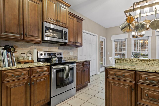 kitchen with light stone counters, decorative backsplash, light tile patterned flooring, and appliances with stainless steel finishes