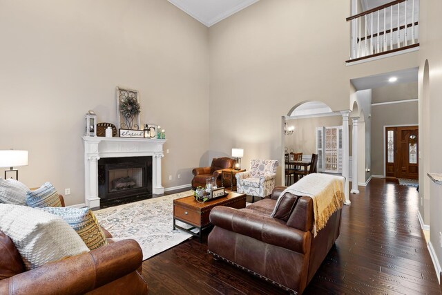 living room with decorative columns, a high ceiling, and dark hardwood / wood-style floors