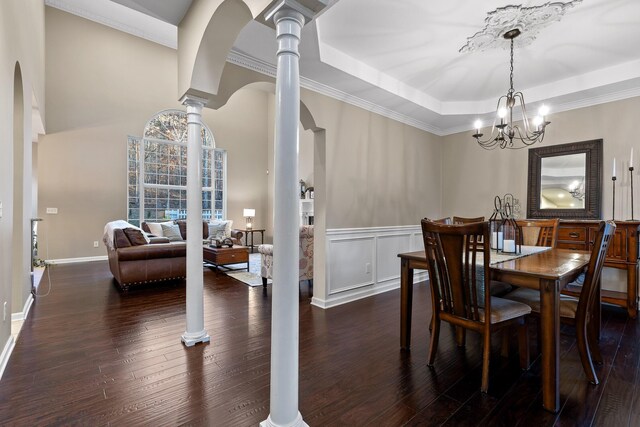 dining room with ornate columns, crown molding, an inviting chandelier, dark hardwood / wood-style floors, and a tray ceiling