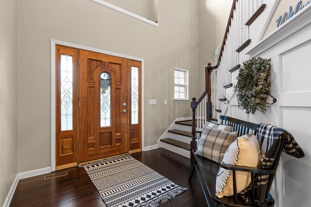 foyer with a towering ceiling and dark wood-type flooring