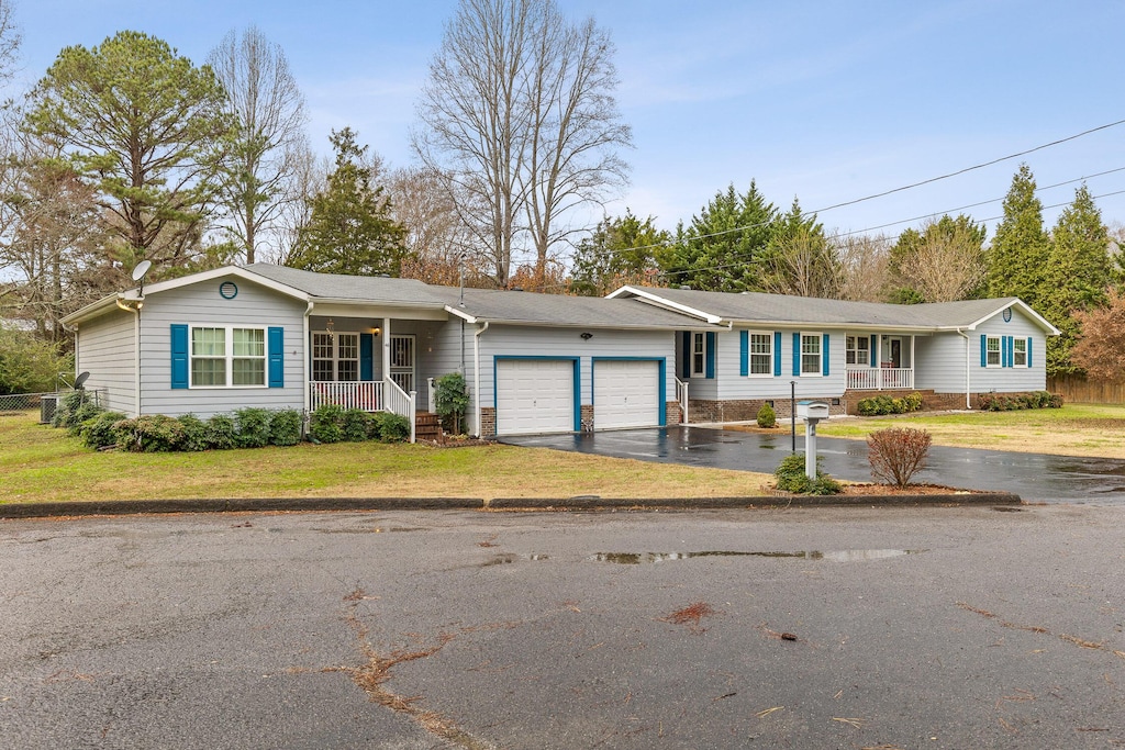 single story home featuring covered porch, a garage, and a front lawn