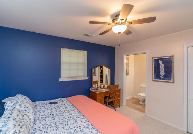 bedroom with ceiling fan, ensuite bathroom, and light carpet